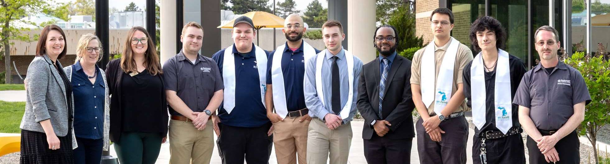 A group of graduates standing outside with staff